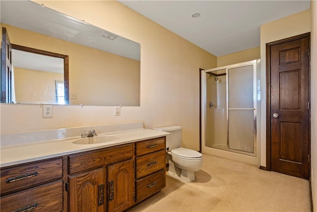 bathroom featuring a shower with door, vanity, and toilet