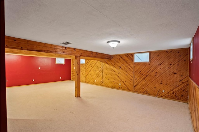 basement with wooden walls, carpet, and a textured ceiling