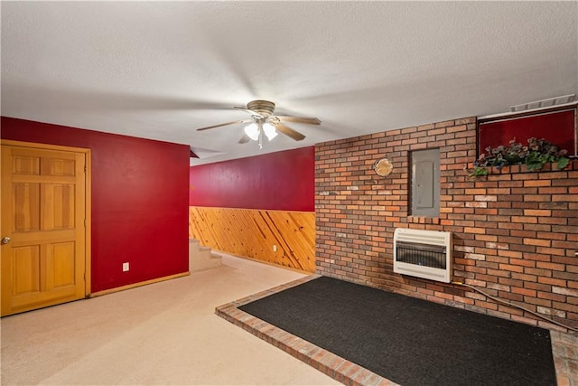 interior space with carpet flooring, a textured ceiling, heating unit, and wooden walls