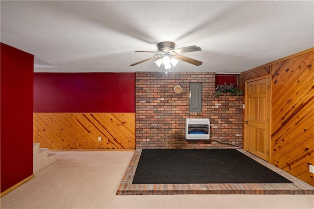 unfurnished living room with wood walls, electric panel, a textured ceiling, carpet floors, and heating unit