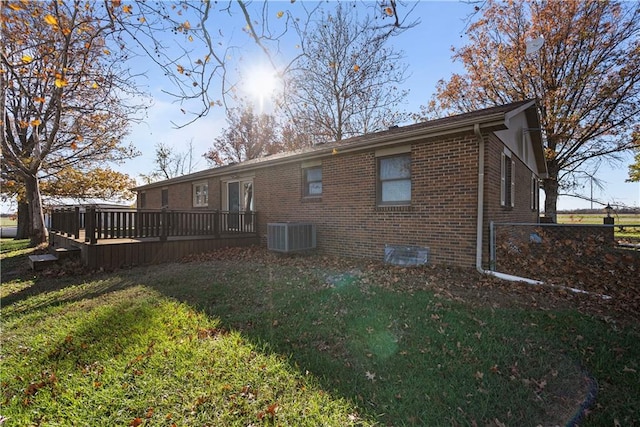 rear view of house with a yard, central air condition unit, and a wooden deck