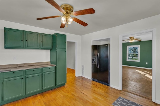 kitchen featuring light hardwood / wood-style flooring, black refrigerator with ice dispenser, and green cabinets