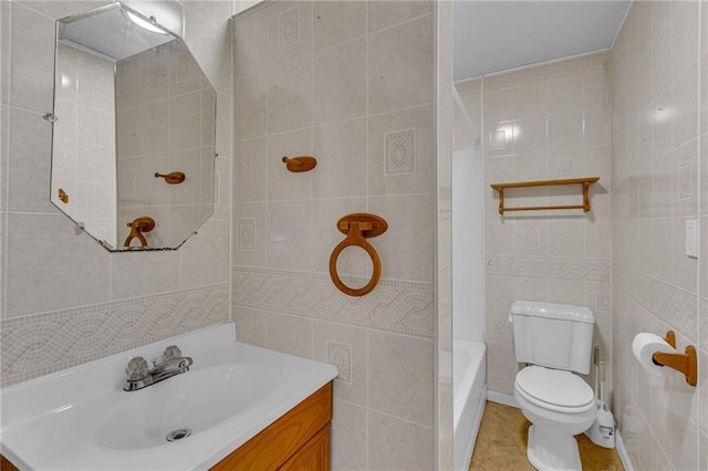 bathroom with vanity, toilet, and tile walls