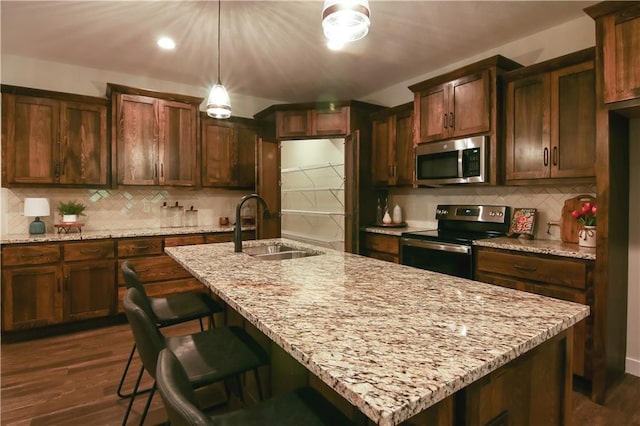 kitchen with light stone countertops, backsplash, stainless steel appliances, dark wood-type flooring, and sink