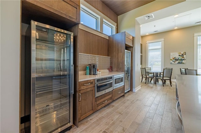 kitchen featuring plenty of natural light, beverage cooler, appliances with stainless steel finishes, and light hardwood / wood-style flooring