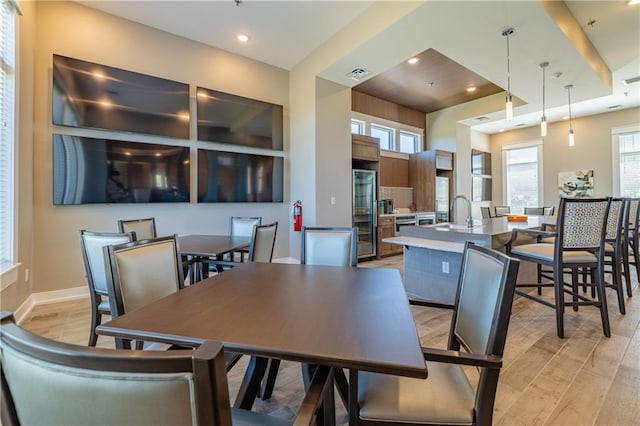 dining area with light hardwood / wood-style floors, a raised ceiling, and sink