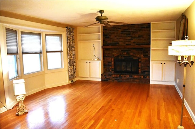 unfurnished living room with hardwood / wood-style flooring, ceiling fan, and a brick fireplace