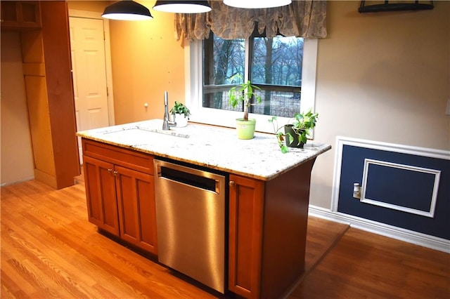 kitchen featuring dishwasher, a center island, sink, light stone counters, and light wood-type flooring