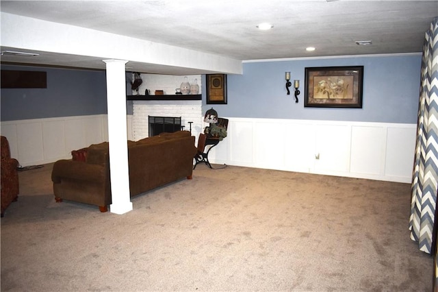 basement featuring carpet floors, a brick fireplace, and crown molding