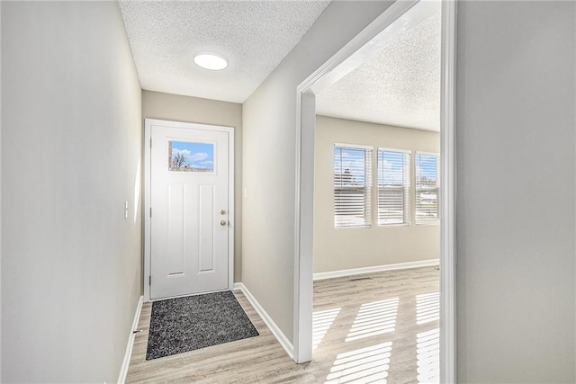 doorway to outside featuring a textured ceiling and light wood-type flooring