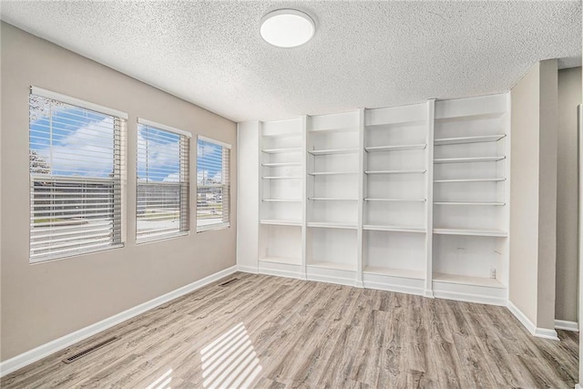 spare room featuring light wood-type flooring and a textured ceiling