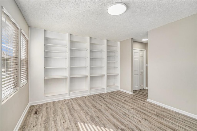 unfurnished room with a textured ceiling and light wood-type flooring