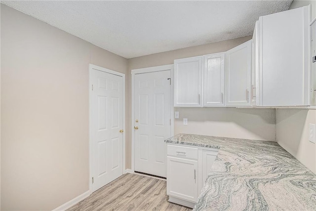 interior space with light stone countertops, light hardwood / wood-style flooring, white cabinets, and a textured ceiling