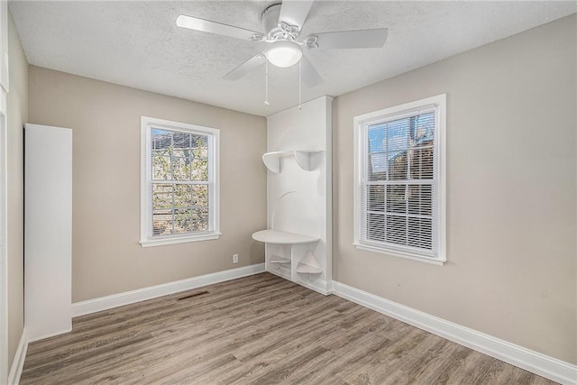 unfurnished room with wood-type flooring, a textured ceiling, and a wealth of natural light