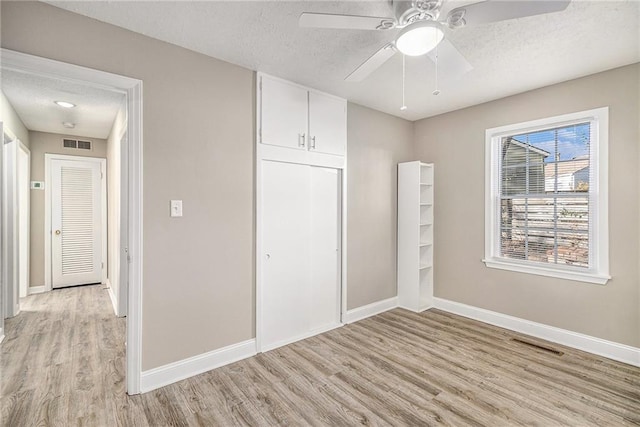 unfurnished bedroom with ceiling fan, a textured ceiling, and light hardwood / wood-style flooring