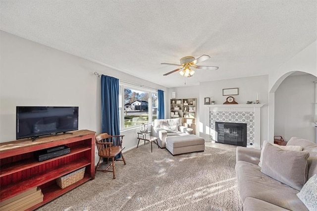 living room with ceiling fan, a fireplace, carpet, and a textured ceiling