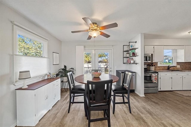 dining area with ceiling fan, light hardwood / wood-style floors, a wealth of natural light, and sink