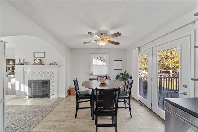 dining area featuring ceiling fan, a textured ceiling, and a tile fireplace