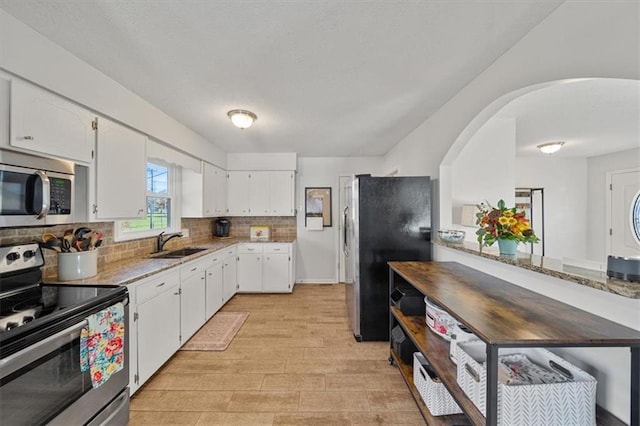 kitchen featuring light stone countertops, white cabinetry, sink, and appliances with stainless steel finishes