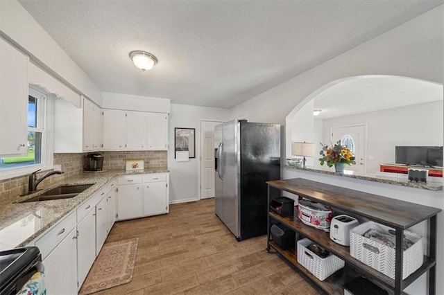 kitchen featuring white cabinets, stainless steel refrigerator with ice dispenser, light wood-type flooring, and sink