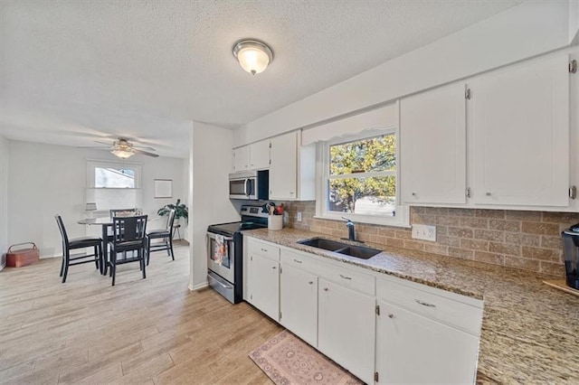 kitchen with white cabinets, sink, ceiling fan, light hardwood / wood-style floors, and stainless steel appliances