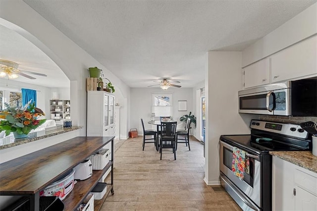 kitchen featuring ceiling fan, stone countertops, white cabinetry, and stainless steel appliances