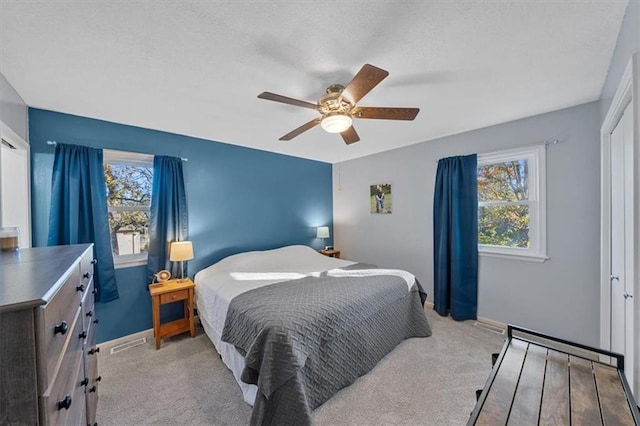 carpeted bedroom with a closet, multiple windows, and ceiling fan