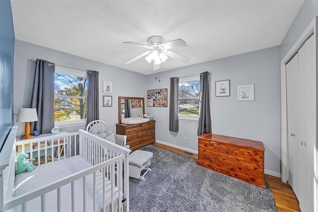 bedroom featuring multiple windows, ceiling fan, a closet, and hardwood / wood-style floors