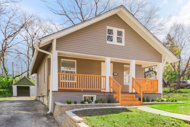 bungalow featuring an outbuilding, a porch, a garage, and a front yard