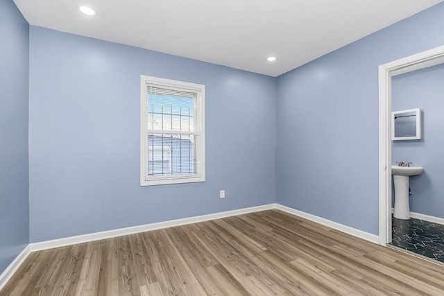 unfurnished room with hardwood / wood-style floors and sink