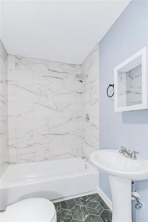 full bathroom featuring tiled shower / bath combo, toilet, and sink