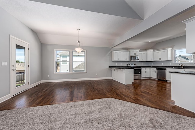 kitchen featuring vaulted ceiling with beams, a healthy amount of sunlight, dark hardwood / wood-style floors, and appliances with stainless steel finishes