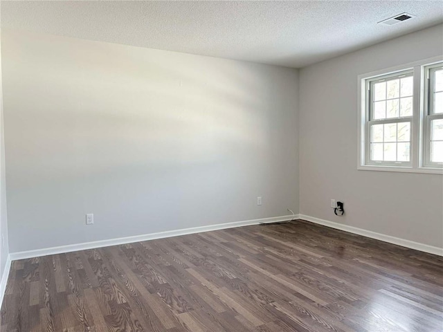 empty room featuring a textured ceiling and dark hardwood / wood-style floors