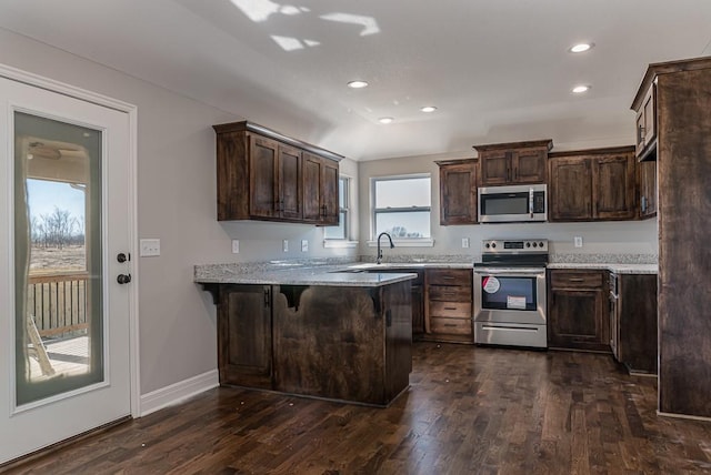 kitchen with kitchen peninsula, dark hardwood / wood-style flooring, a breakfast bar, dark brown cabinetry, and stainless steel appliances