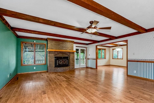 unfurnished living room with hardwood / wood-style flooring, ceiling fan, and beamed ceiling