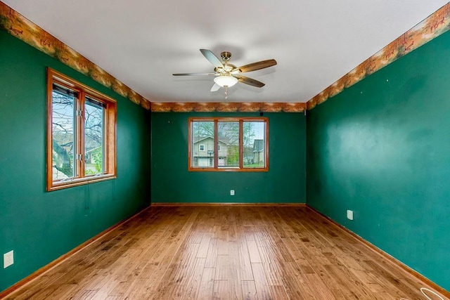 spare room with ceiling fan, a wealth of natural light, and light hardwood / wood-style flooring