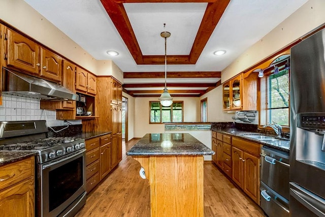 kitchen featuring sink, stainless steel appliances, decorative backsplash, a kitchen island, and light wood-type flooring