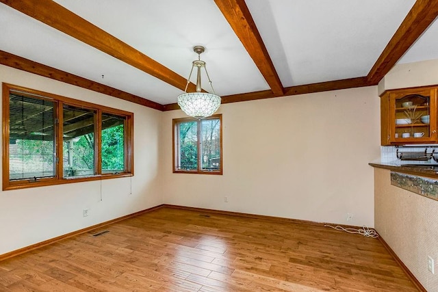 unfurnished dining area with beam ceiling and light hardwood / wood-style floors