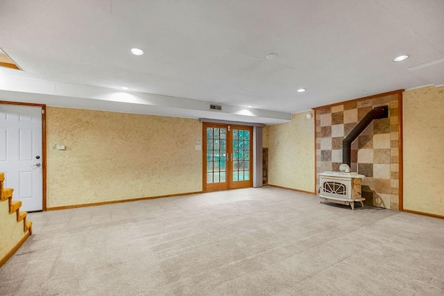 interior space featuring light colored carpet, a wood stove, and french doors