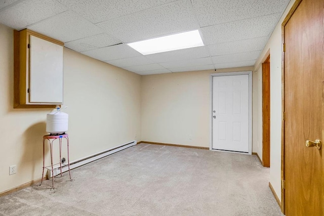 empty room featuring baseboard heating, a paneled ceiling, and light carpet