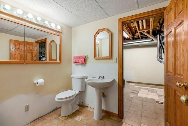 bathroom featuring a paneled ceiling, sink, tile patterned flooring, and toilet