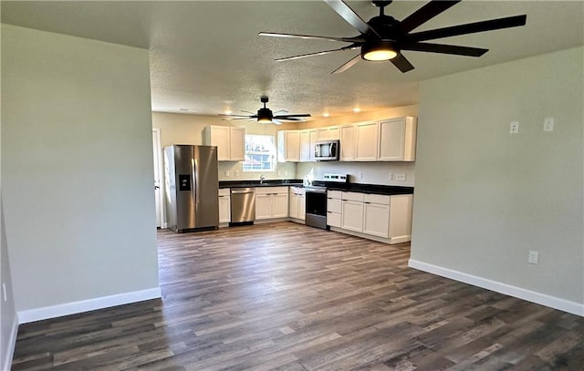 kitchen featuring appliances with stainless steel finishes, a textured ceiling, white cabinetry, and dark wood-type flooring