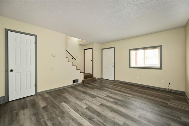 unfurnished room with a textured ceiling and dark hardwood / wood-style floors