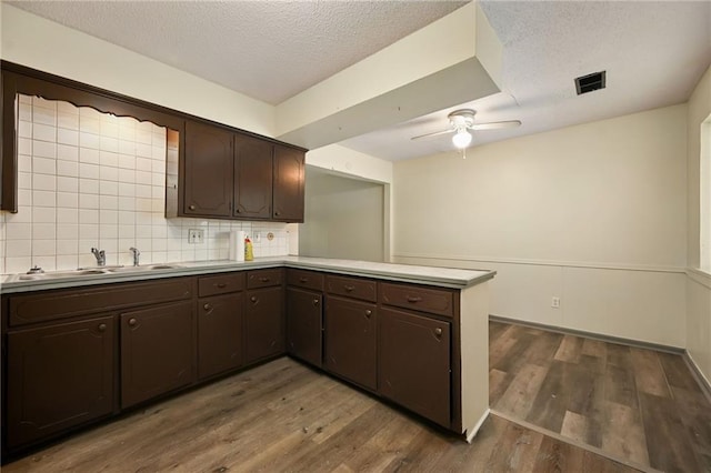 kitchen featuring kitchen peninsula, dark brown cabinetry, dark hardwood / wood-style floors, and sink