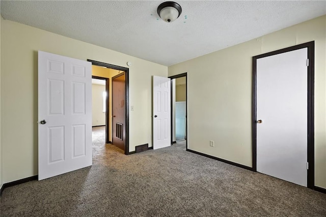 unfurnished bedroom with a textured ceiling and dark colored carpet