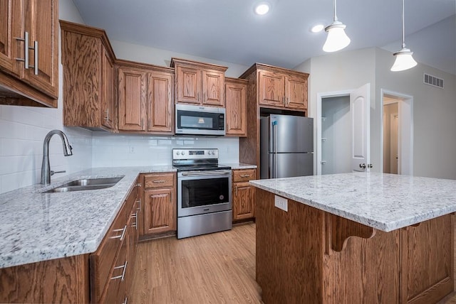 kitchen with backsplash, stainless steel appliances, sink, decorative light fixtures, and light hardwood / wood-style floors