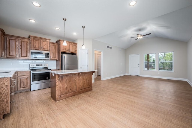 kitchen with light wood-type flooring, stainless steel appliances, ceiling fan, a center island, and lofted ceiling