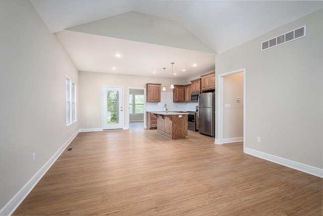 kitchen featuring pendant lighting, a kitchen island, light wood-type flooring, and appliances with stainless steel finishes