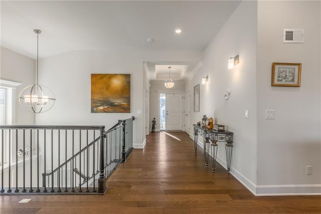 hall with a chandelier, dark wood-type flooring, and a healthy amount of sunlight