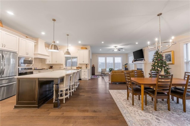 kitchen featuring a center island, backsplash, premium range hood, hanging light fixtures, and built in appliances